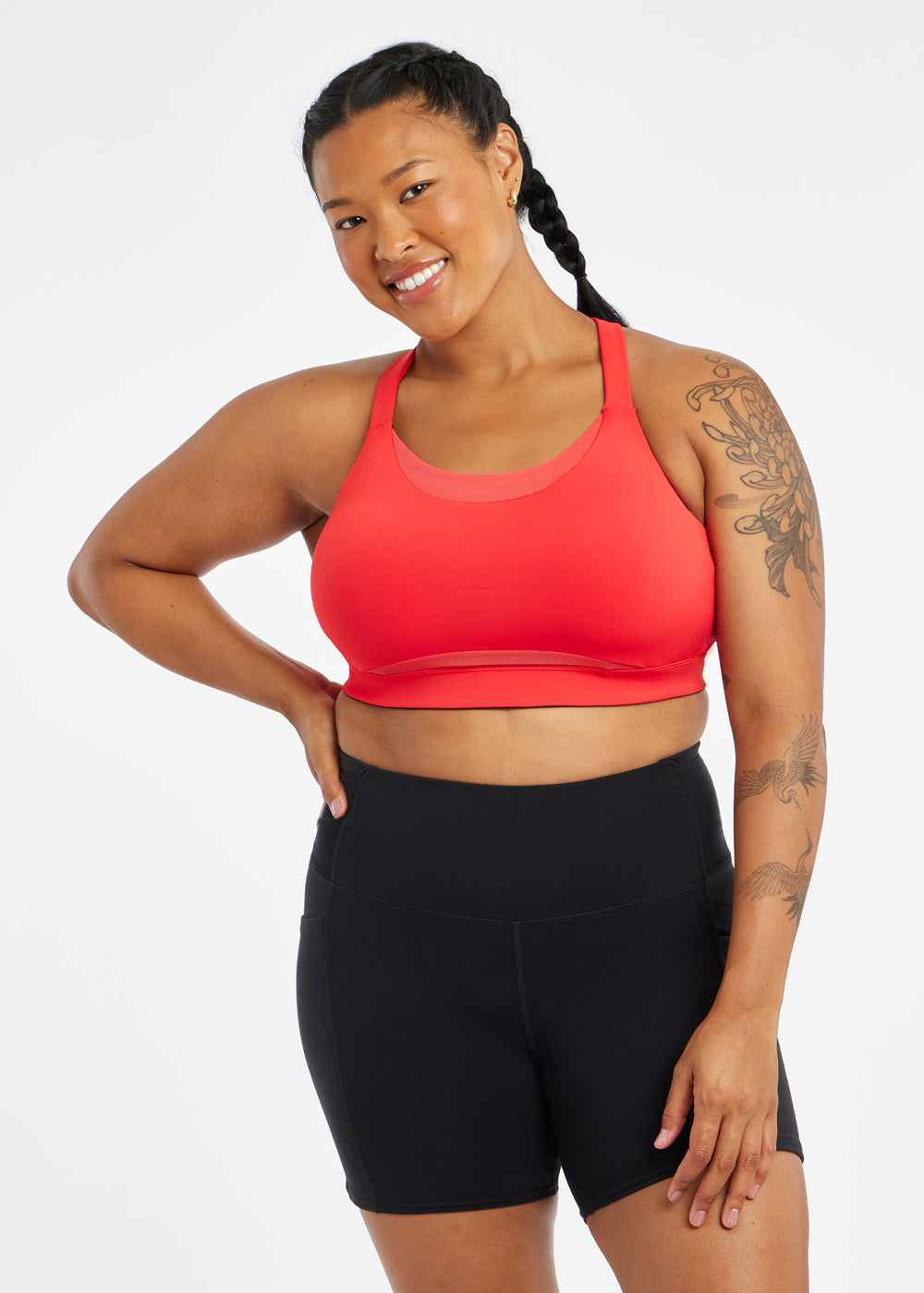 Woman wearing red orange band and cup sports bra, front view