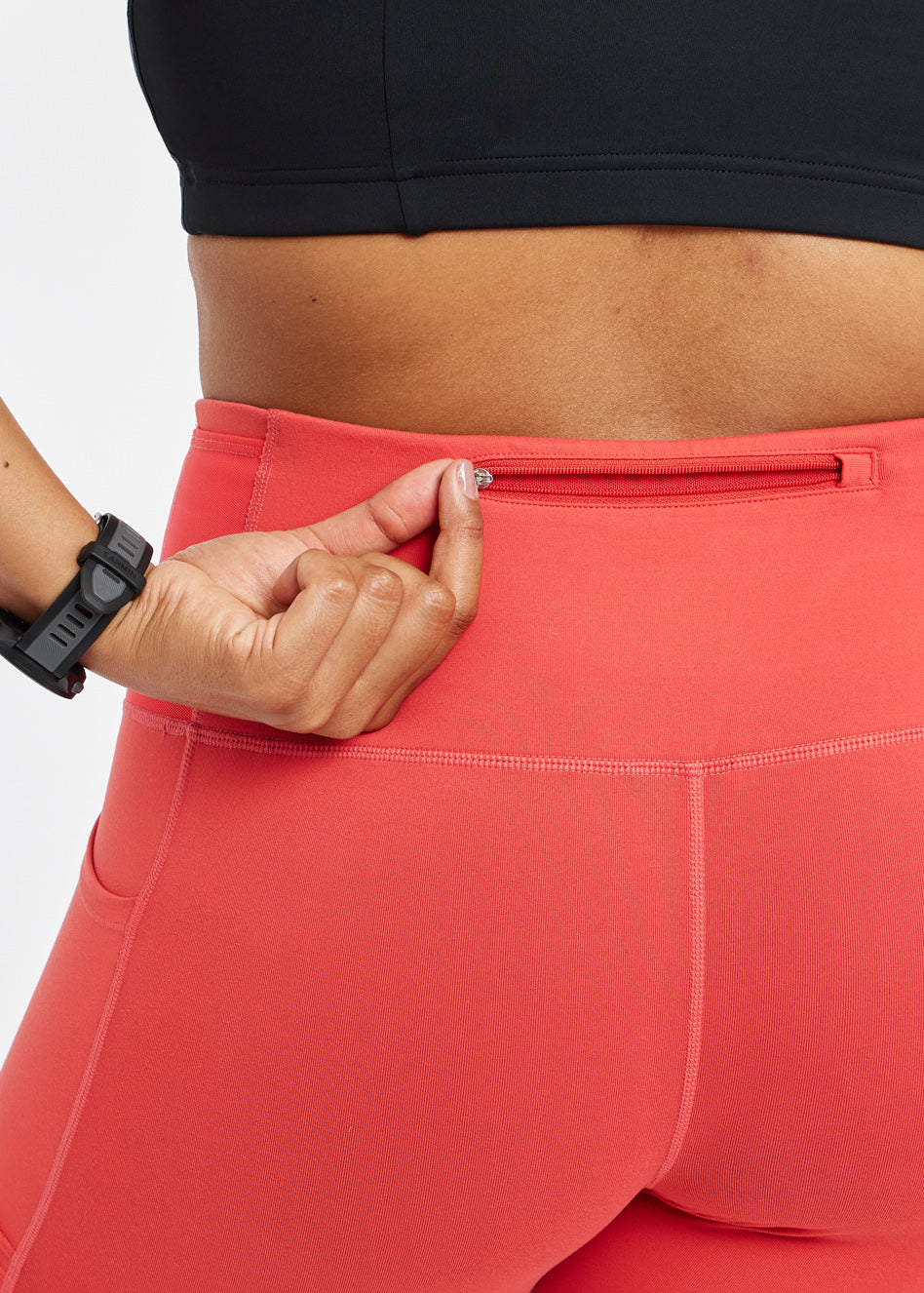 Woman wearing red orange compression tights, close up of back zipper pocket