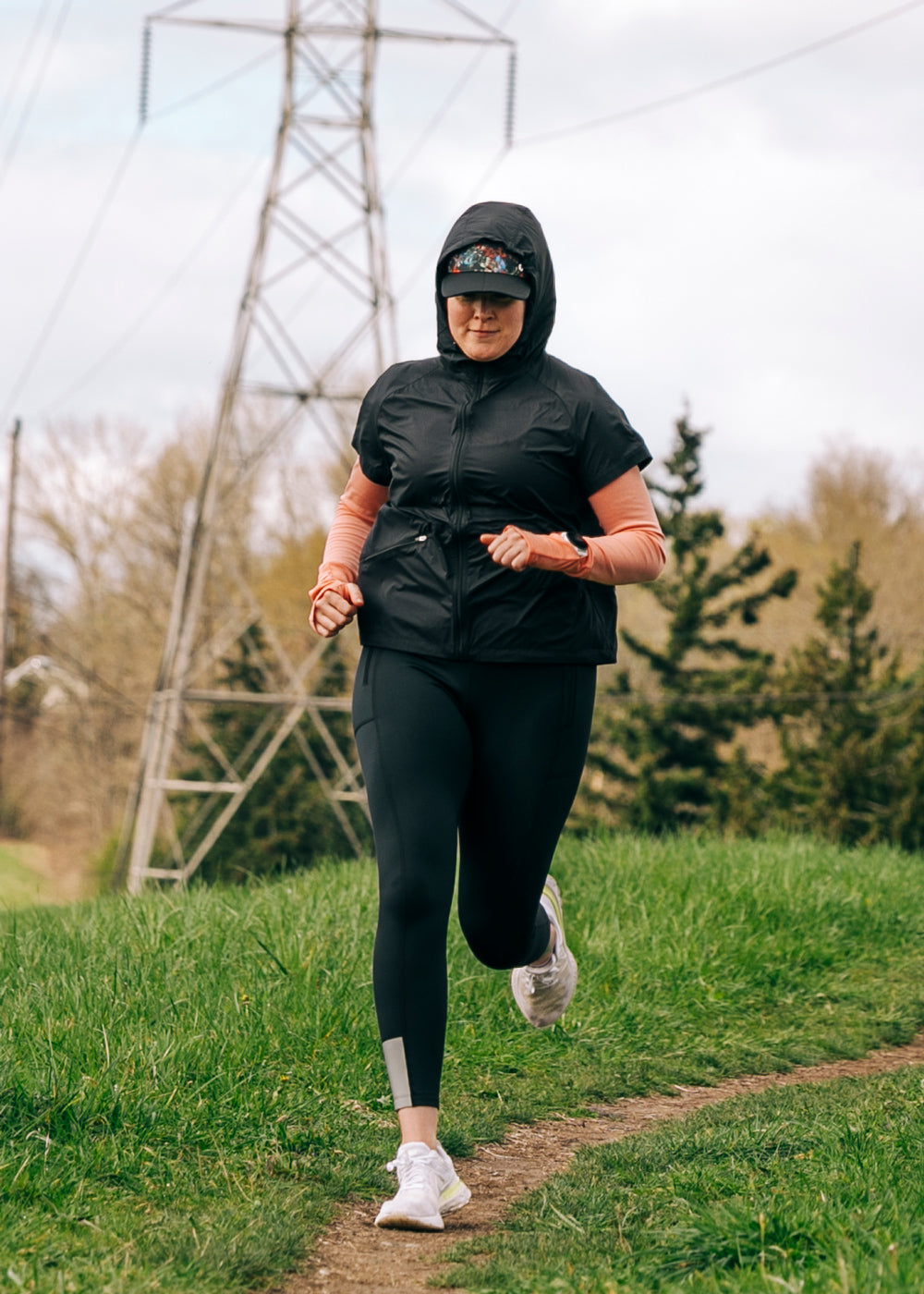 Run Poncho in Black, woman running on a trail
